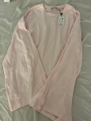 Ljusrosa långärmad topp från lager 157 - Säljer en enkel och stilren ljusrosa långärmad topp från lager. Toppen har rund halsringning och är tillverkad i mjuk bomull, perfekt för en avslappnad look. Passformen är normal och materialet känns skönt mot huden. Tight mot magen o pösig i armarna