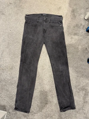 Replay jeans - Snygga grå jeans från Replay i slim fit-modell. Klassisk femficksdesign med detaljerade sömmar och knappgylf. Jeansen har en tvättad look.