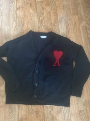 Svart cardigan med rött hjärta Ami - En snygg ami paris cardigan. Jag säljer den för att den är för liten. 
