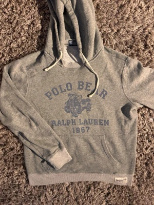 Grå hoodie Polo Bear Ralph Lauren🙌🤩 - Grå hoodie från Ralph Lauren med Polo Bear-tryck och texten '1967' på bröstet. Hoodien är i storlek S och riktigt najs🤩🙌