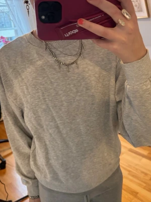 Grå sweatshirt i mjuk bomull - Säljer en basic grå sweatshirt i mjuk bomull med rund halsringning och ribbade muddar vid ärmslut och midja. Perfekt för lager-på-lager och chill dagar. Enkel och stilren design utan tryck eller logga.