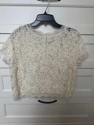 Vit spets topp - romantisk & elegant - Vacker vit topp i spets med fina detaljer. En kortare modell som är perfekt till jeans eller kjol. Väldigt romantisk och somrig stil. Perfekt till fest, semester, midsommar eller student. 🤍 Väldigt fin spets 🤍 Lätt och luftig 🤍 Fint skick Hör av dig om du har frågor!