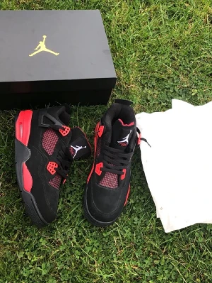 Air Jordan 4 Retro Black/Red - Snygga Air Jordan 4 Retro sneakers i svart mocka med röda och grå detaljer. Klassisk siluett med högt skaft, meshpaneler och Jumpman-logga på plösen. Perfekta för dig som vill sticka ut med en ikonisk och sportig look. Vid snabb affär kan priset pratas om