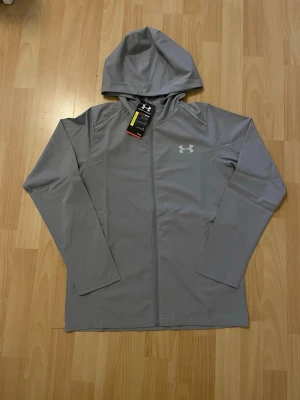 Under Armour Jacka - Grå Under Armour jacka/vindjacka helt ny i storlek M, men passar som S/XS. Den har väl fungerande reflex. Kommer med dustbag och tags. Mått finns. Prisförslag eller frågor är välkomna! 🙏💬 Obs: Dustbag/Påsen är lite sliten.