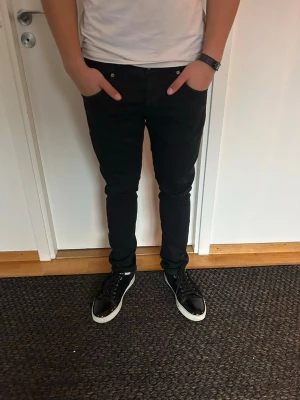 Dondup jeans - Snygga svarta slim fit jeans från dondup med klassisk femficksdesign och diskreta detaljer. Jeansen har smal passform och sitter tajt längs benen, perfekta för en modern och stilren look. Passar dig som gillar minimalistisk stil och vill ha ett par jeans som funkar till allt. Nypris 4000