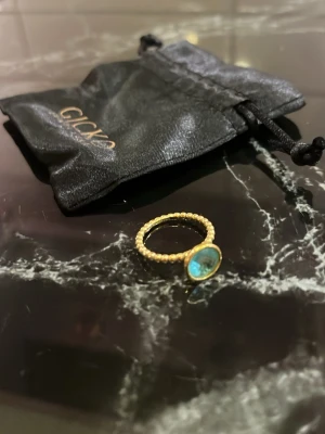 Guldpläterad ring med Topaz sten - Snygg ring från Gicko med guldpläterad pärlstruktur runt hela ringen och en stor blå topaz i centrum. Ringen har en modern och trendig design som sticker ut och passar perfekt för dig som gillar unika accessoarer. Storlek 16