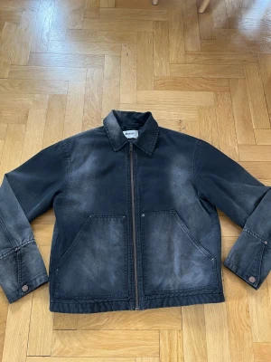 Weekday jeansjacka - Snygg svart jeansjacka från Weekday med tvättad look och raka linjer. Jackan har två stora fickor framtill, dragkedja och klassisk krage. Perfekt för dig som gillar en avslappnad och trendig stil. Bra skick köpt förra året. XS men passar även S-M. Priset är diskuterbart.