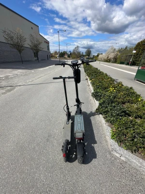 Svart elscooter med breda däck - Säljer en svart elscooter med breda däck och robust ram. Scootern har dubbla handtag, display på styret och fotplatta med grått mönster. Perfekt för att ta sig runt i stan på ett smidigt sätt.