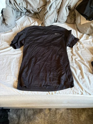 Svart t-shirt från MAN - En stilren svart t-shirt från MAN med diskret logga på bröstet. Klassisk passform och rund halsringning. Perfekt basplagg till garderoben och enkel att matcha med allt. Tillverkad i mjukt bomullsmaterial för skön känsla.