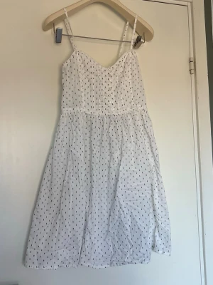 Vit sommarklänning från LTB Jeans - Söt vit kortklänning från LTB Jeans med tunna axelband och små blå mönster. Klänningen har knappar framtill 