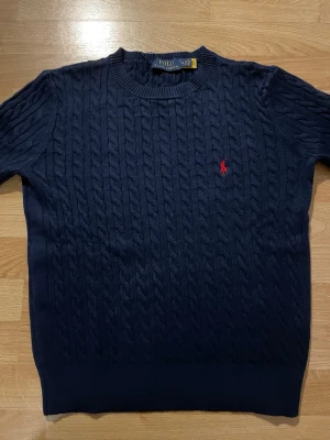 Mörkblå kabelstickad tröja Polo Ralph Lauren - Mörkblå kabelstickad tröja från Ralph Lauren. Helt ny och aldrig använd. Är storlek M, men upplevs som något mindre (mer som S i passformen). Klassisk och stilren modell som passar till det mesta.  Hör av dig om du har frågor! 😃