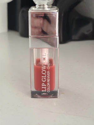 Dior Lip Glow Oil Cherry - Säljer ett Dior Lip Glow Oil i färgen Cherry. Läppoljan kommer i en genomskinlig fyrkantig förpackning med silverfärgat lock och har en rödrosa ton. Produkten ger glans och återfuktar läpparna med en lätt oljig känsla.mer än halv kvar