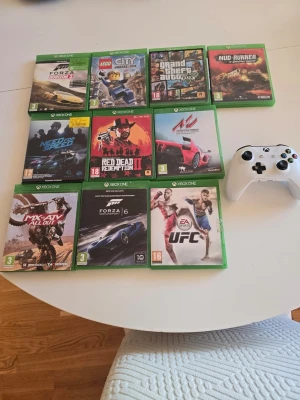 Xbox One spelpaket med 10 spel - Säljer ett paket med 10 Xbox One-spel, bland annat Forza Horizon 2, LEGO City Undercover, GTA V, MudRunner, Need for Speed, Red Dead Redemption II, Assetto Corsa, MX vs ATV All Out, Forza Motorsport 6 och EA Sports UFC. Perfekt för dig som gillar racing, äventyr och sport. Handkontrollen fattas batteri locka 