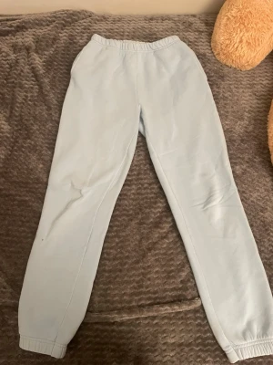 Ljusblå mjukisbyxor från Gina Tricot - Säljer ett par ljusblå mjukisbyxor från Gina Tricot, basically basics-kollektionen. Byxorna har resår i midjan och vid bensluten, raka ben och är gjorda i mjukt, fleeceliknande material. Perfekta för chill dagar eller när du vill vara extra bekväm.