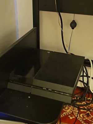 PlayStation 4 svart spelkonsol - Säljer en svart PlayStation 4 från Sony. Konsolen har en stilren, rektangulär design med matta och blanka ytor. Perfekt för gaming och streaming. Passar till alla som vill ha en kraftfull spelupplevelse hemma.