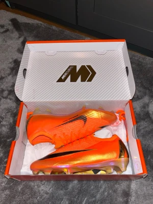 Nike Mercurial Vapor 16 elite Déjà vu limited edition (SPRILLANS NYA) - Säljer ett par Nike Mercurial fotbollsskor i en riktigt snygg orange färg med svarta detaljer och en skinande sula. Skorna har låg profil och är tillverkade i ett lätt syntetmaterial för maxad speed och kontroll på planen. Perfekta för dig som vill sticka ut på matchen. Skorna är helt nya och aldrig använda och är limited edition så dom går inte att få tag på längre.