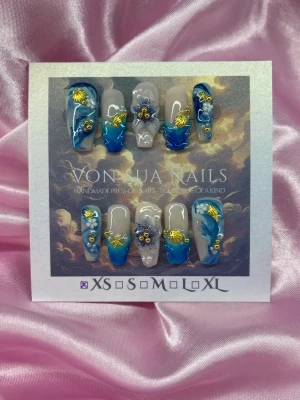 Ocean Muse (XS);Medium Ballerina - Unika handgjorda press-on naglar i blått och nude. Naglarna har handgjorda 3D-blommor, guldfärgade detaljer och små pärlor. Formen är medium ballerina och i storlek ; XS: 14 mm, 11 mm, 11,5 mm, 10 mm, 8 mm . Perfekt för dig som vill sticka ut med en kreativ och trendig nageldesign.