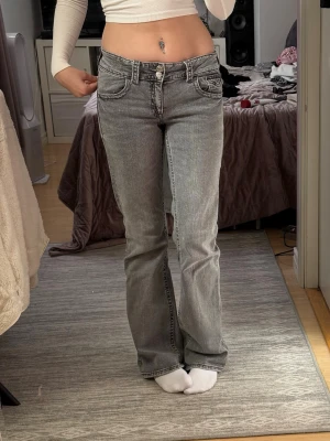 Grå bootcut jeans med låg midja - Säljer ett par grå bootcut jeans med låg midja och klassiska fem fickor. Jeansen är straight/bootcut. Storlek 170 (passar de som är runt 170cm långa) sitter som S