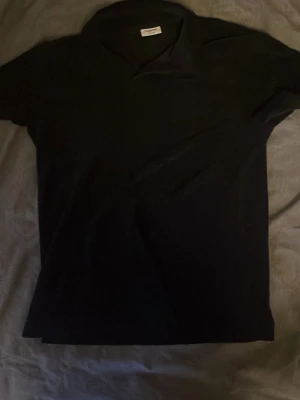 Svart pikétröja i frotté  - Klassisk svart frottetröja med krage och korta ärmar. Tillverkad i mjuk frotee som känns skön mot huden. Enkel och stilren design som passar till det mesta. Perfekt för dig som gillar en clean och tidlös look.