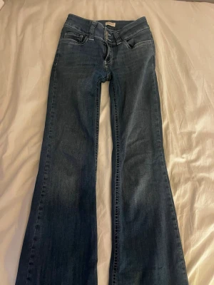 Mörkblå bootcut jeans från Nelly - Trendiga jeans från Nelly. Inte helt säker på storleken men tror det var 32 eller 34. Dom är lite för långa för mig som är runt 160cm köpte för 700 säljer för 500 pris kan diskuteras 