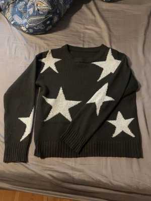 Svart stickad tröja från SHEIN - Cool svart stickad tröja från SHEIN med stora gråa stjärnor över hela tröjan. Tröjan har rund halsringning, långa ärmar och är gjord i 100% polyester. Storlek XS