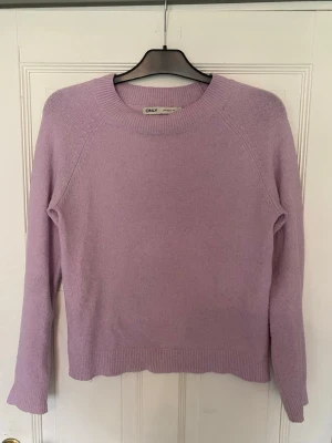 Rosa stickad tröja från ONLY - Säljer en enkel och snygg rosa stickad tröja från ONLY. Tröjan har rund halsringning, långa ärmar och ribbade muddar vid ärmslut och nederkant. Perfekt för lager på lager och ger en soft vibe till din outfit.