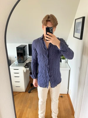 Marinblå linneskjorta från Massimo dutti - Snygg marinblå skjorta i linne från Massimo dutti. Skjortan har klassisk krage, knappar framtill och lång ärm. Det följer även med 2 extra knappar. Hör gärna av dig vid frågor!