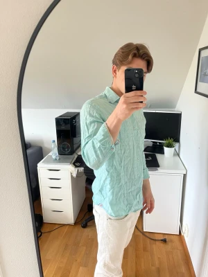 Ljusblå skjorta i linneblandning - Snygg ljusgrön skjorta i linneblandning från Tommy bahama med klassisk krage och knappar framtill. Skjortan har lång ärm och en avslappnad passform. Hör gärna av dig vid frågor!