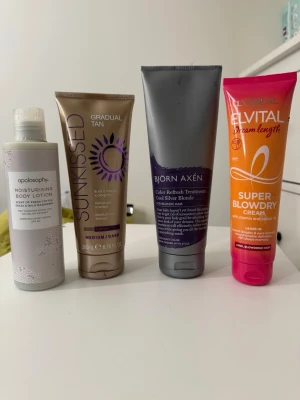 Blandade skönhetsprodukter 4-pack - Fyra olika skönhetsprodukter: en återfuktande body lotion från Apolosophy, en gradual tan brun utan sol från Sunkissed (medium/dark), en silverinpackning för blont hår från Björn Axén och en värmeskyddande blowdry cream från L'Oréal Elvital. Perfekt för dig som vill boosta både hud och hår.