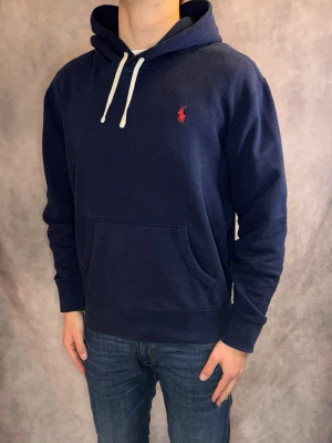 Marinblå Ralph Lauren Hoodie - Stl M - Riktigt snygg Ralph Lauren Hoodie i färgen marinblå | Mycket bra skick: 8,8/10, inga defekter | Stl: M, modellen är 177cm och väger 75kg, passar perfekt | Nypris: Ca 2000kr | Hör av dig vid frågor // Galgen 🫡