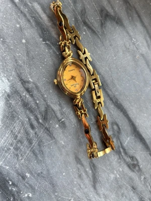 Guldig klocka - Söt guldig klocka med orange urtavla. Fint skick! 