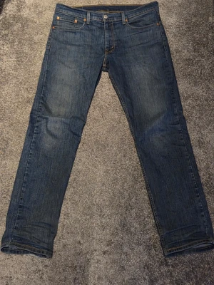 Levi's 502 - Säljer nu mina Levis 502, klassiska blå jeans från Levi's straight fit. Jeansen har en snygg tvättad look och detaljer i kopparfärg. Lägger sig perfekt på skorna! Bara att höra av sig vid några funderingar! L32 W33