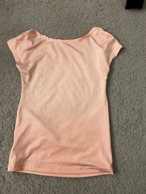 Ljusrosa öppen rygg - Snygg ljusrosa topp i mjukt material med ärmlös design och rund halsringning. Perfekt för dig som gillar en enkel och clean stil. Passar till både jeans och kjol för en fräsch look.