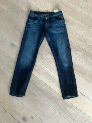 Mörkblå jeans från Replay - Snygga mörkblå jeans från Replay, modell WALEYS. Klassisk femficksdesign med dragkedja och knapp. Jeansen har en smal passform och kontrastsömmar. Tillverkade i bomull med lite stretch för extra komfort. Dem är upplagda uniefär 5 cm altså lite kortare än när man köper i butik.