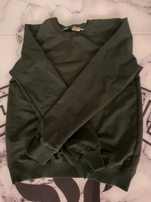 Tröja  - En enkel och stilren mörkgrön sweatshirt från Wiyola. Perfekt för dig som gillar basic och tidlös stil.