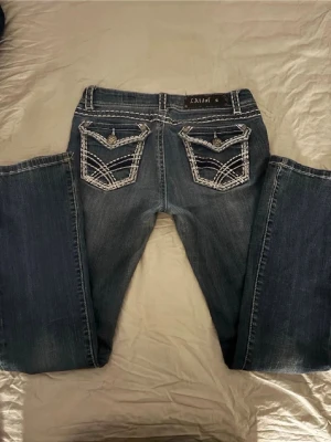 Mörkblå bootcut-jeans  - Lowwaist La idol jeans med coola fickor. Sömmar längst byxorna. Storleken är 9 vilket motsvarar S/M. Jaa har lappat dem i skrevet då de va lite slitna så ja sydde på en tygbitar på insidan. Jag är 168 och dom passar ganska bra på mig, lite långa.