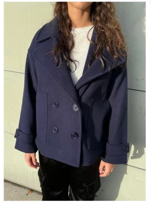 Mörkblå dubbelknäppt ullrock - Säljer en mörkblå kort kappa eftersom jag inte använder den längre.