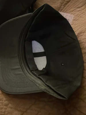 Svart klassisk keps i bomull - Säljer en stilren svart keps med böjd skärm och justerbar baksida. Kepsen är tillverkad i bomullstyg sopassar till sopassar till alla tillfällen. Enkel design utan logga eller tryck, perfekt för dig som gillar en clean look.