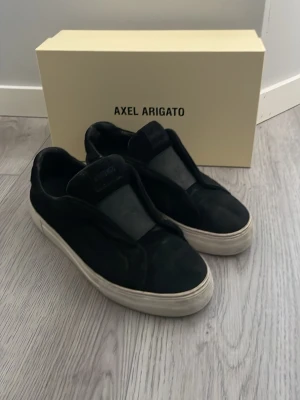 Axel arigato skor - Svarta sneakers från Axel Arigato i storlek 42. Vänstra skon har släppt lite på insidan (bild 3) men syns knappt och märks inte när man har dom på sig. Pris kan diskuteras vid snabb affär!