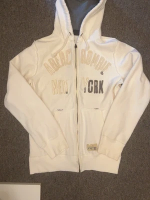 Vit luvtröja Abercrombie & Fitch - Säljer denna  Abercrombie & Fitch luvtröja. Jag har använt den ett tag men lappen har jag sparat på för den var lite för stor för mig, så dendär inte tvättad så kan vara lite smutsig men det går bort efter en tvätt. Kontakta vid frågor:)