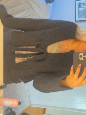 Svart stickad_rekofta med knytband - Säljer en svart stickad kofta med långa ärmar och knytband framtill. Perfekt att slänga över ett linne för en chill look. Aldrig använd!!!🥰