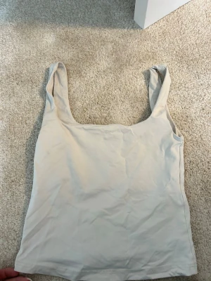 Vitt linne från NA-KD - Säljer ett vitt linne från NA-KD. Toppen har breda axelband och en rak, enkel passform som är lätt att matcha med olika outfits. Perfekt för dig som gillar en clean och basic look.