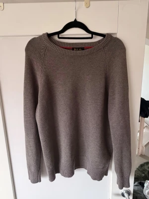 Grå stickad tröja med rund hals från loro piana - En enkel och stilren grå stickad tröja med rundad halsringning och långa ärmar. Tröjan har ribbade muddar vid ärmslut och nederkant, perfekt för lager på lager och en clean look.