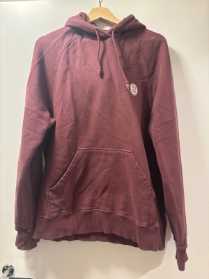 Vinröd hoodie från Nudie jeans - Bra skick. Mjuk. Herrmodell. Storlek M