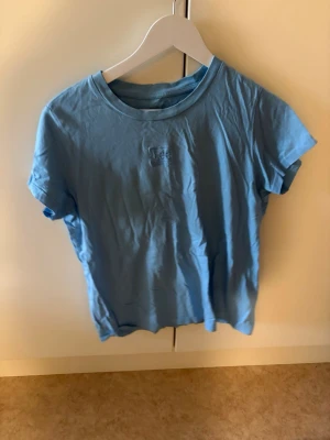 Ljusblå kortärmad t-shirt Lee - Säljer en ljusblå t-shirt från Lee med diskret logga på bröstet. T-shirten har klassisk rund halsringning och korta ärmar. Tillverkad i mjuk bomull som känns skön mot huden. Perfekt till jeans eller shorts för en enkel och clean look.