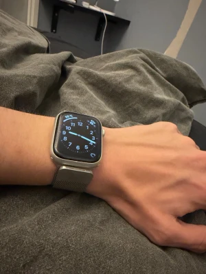 Apple Watch Series 8 gps+ cellular 45mm - Snygg Apple Watch med fyrkantig skärm och silverfärgat mesh-armband i rostfritt stål. Klockan har en modern design med digital display och touchfunktion. Perfekt för dig som vill ha koll på notiser, hälsa och träning direkt på handleden.