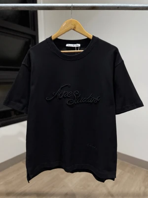 Svart Acne Studios t-shirt - Snygg svart t-shirt från Acne Studios med broderad logga framtill. Klassisk rund halsringning och korta ärmar. Tillverkad i mjuk bomull för en skön känsla och stilren look.