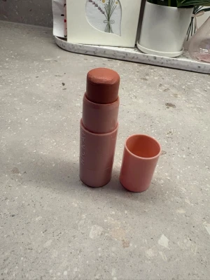 Krämrouge stick Hickap - Säljer en krämrouge i stickformat med varm rosa ton. Förpackningen är cylinderformad och går i en matchande rosa nyans. Enkel att applicera direkt på kinderna för en naturlig glow. Perfekt att ha i väskan för snabba touch-ups.