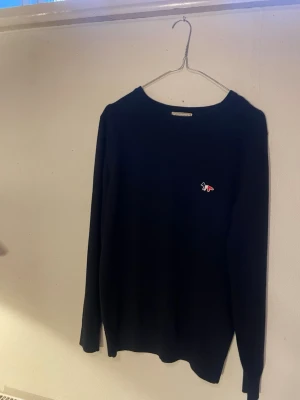 Maison kitsuné tröja - Säljer en snygg stickad tröja från maison kitsuné. Har en lätt defekt i armhålan som är lagad och som knappt syns. Storleken är M/S Hör av er vid frågor!❤️‍🩹
