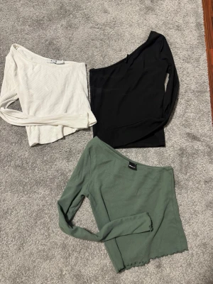 Off shoulder toppar - Säljer tre långärmade offshoulder toppar, i färgerna vit, svart och grön. Använd ett få tal gånger. Storlek s. Säljer alla tre tillsammans.